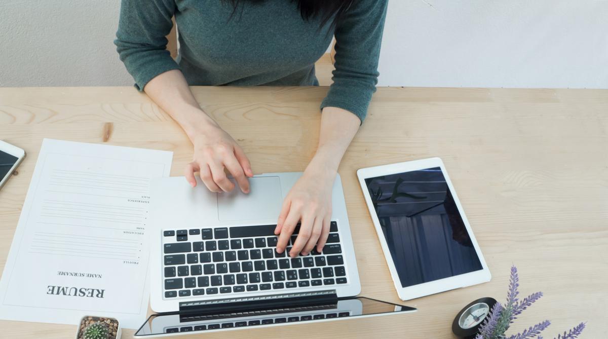 Female at a desk with a resume, computer, and tablet