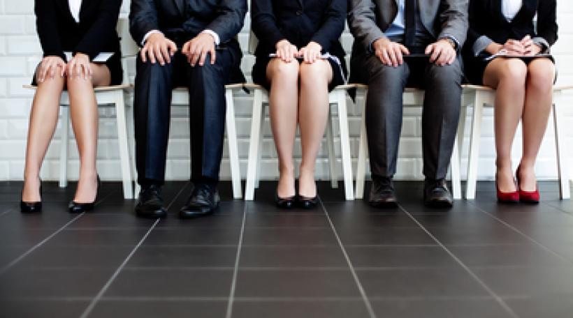 Five people professionally dressed sitting on a bench, seen from torso down to floor