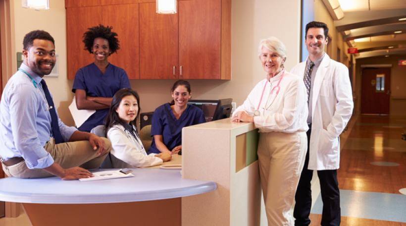 Group of hospital employees at hospital station looking at viewer