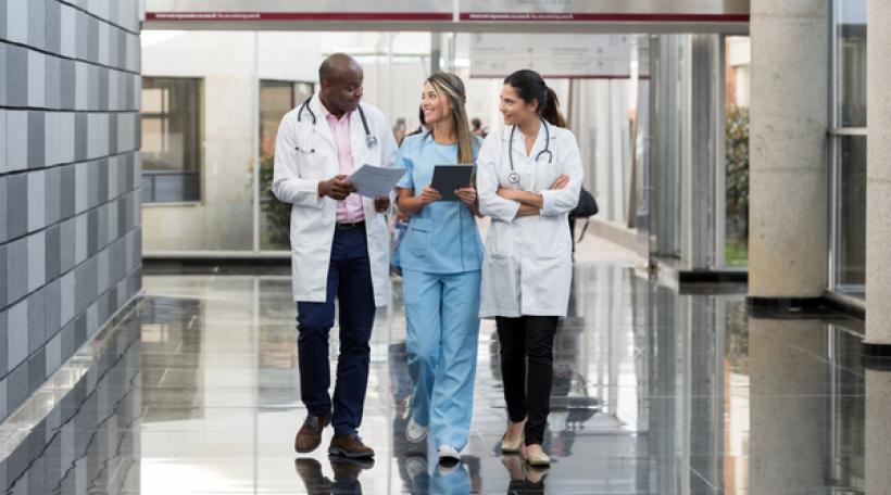 Small group of health care professionals walking down hospital hallway