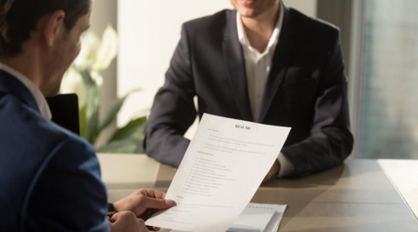 Two people conducting a professional job interview, one looking at resume