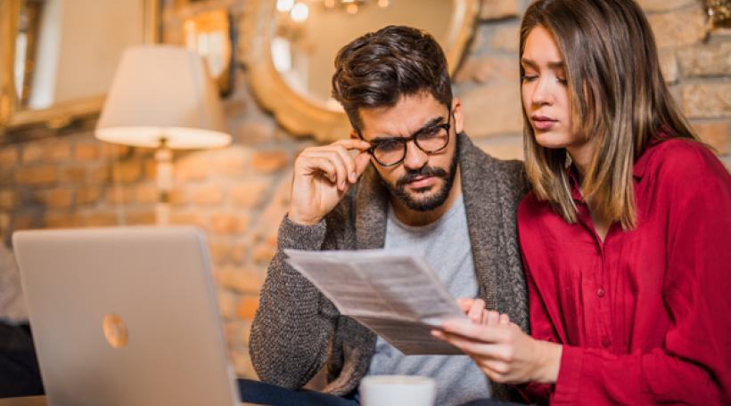 Couple reviewing paperwork in front of a laptop