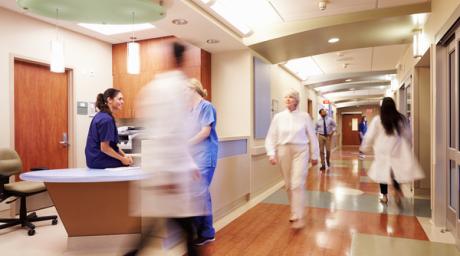 Blurred image of health care professionals bussling through a hospital hallway