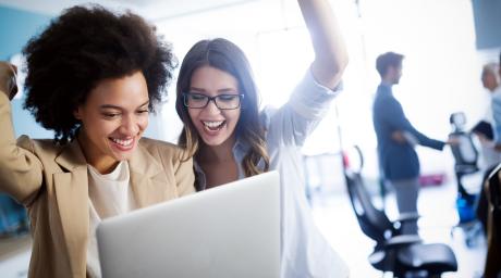 Two women smiling at laptop