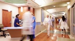 Blurred image of health care professionals bussling through a hospital hallway