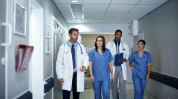 Group of health care professionals talking while walking down hallway of medical facility